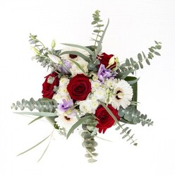 Arranged with the artistry and care reflective of East Ham Florist's longstanding heritage, this bouquet is a testament to thoughtful composition and fresh beauty. Central to the ensemble, deep red roses spiral open, their layered petals rich with meaning, while snowy white gerbera daisies with their chocolate centers provide an anchoring sense of classic joy. Eucalyptus leaves, silvery and cool, arch above and around, their smooth discs adding both motion and a refreshing aroma that calls to mind tranquil afternoons on High Street South. Delicate, lilac lisianthus blooms peek through, introducing contemporary flair and a touch of serene romance as subtle as the morning hush in Plashet Park. Fluffy clusters of white filler flowers create a sense of fullness and soft contrast, like the clouds that drift over East Ham's skyline. All elements are expertly cradled by sculptural deep green leaves, wrapping the base with a confident polish that showcases the florist's skill. The clear vase reveals sturdy, fresh stems standing in crisp water, a visible promise of longevity and care. Each flower is selected not only for its beauty, but for its ability to evoke warmth, comfort, and celebration-perfect for local anniversaries, heartfelt thanks, or sympathetic gestures within the East Ham community.